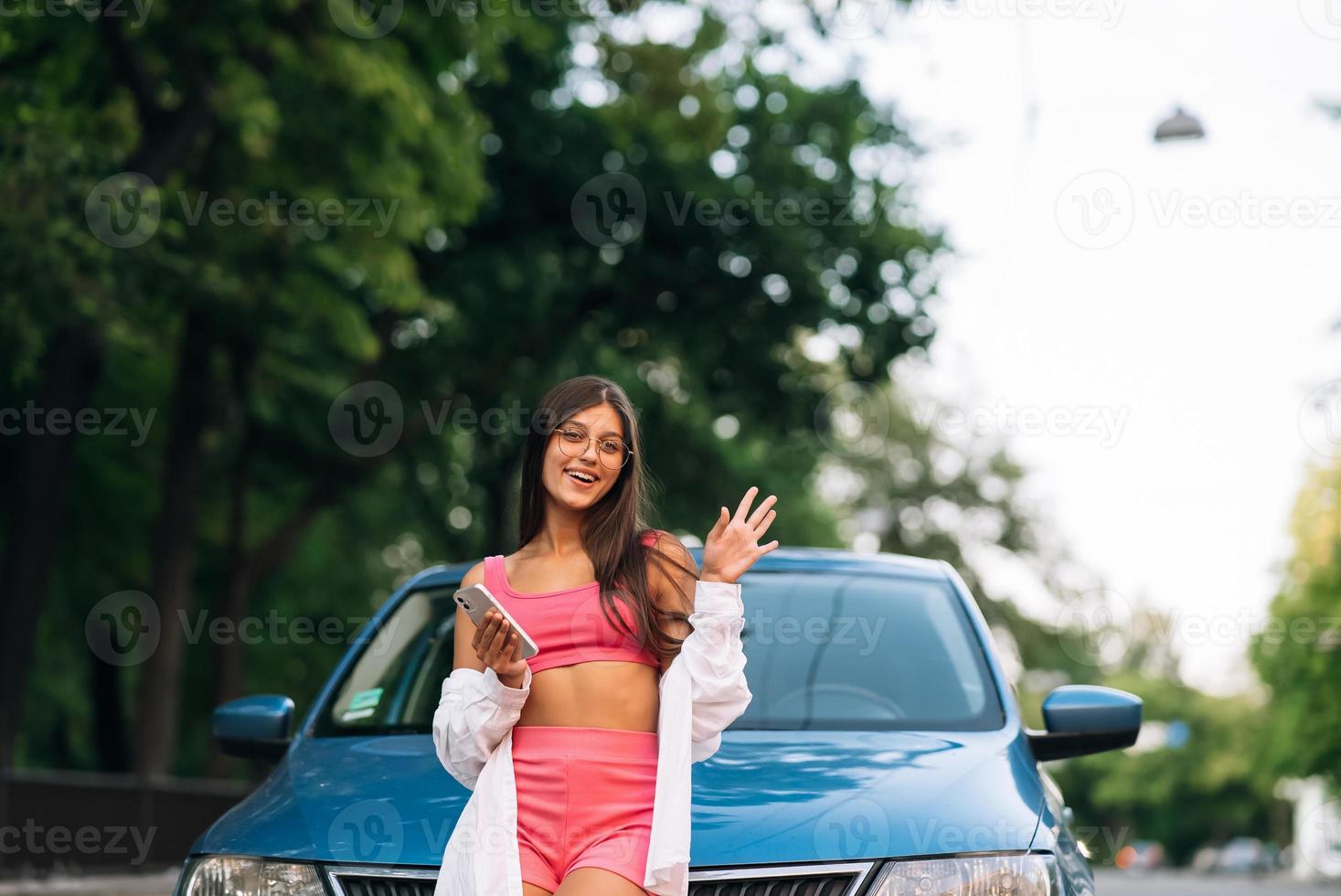 Frau mit Handy in der Nähe des Autos auf der Straße foto