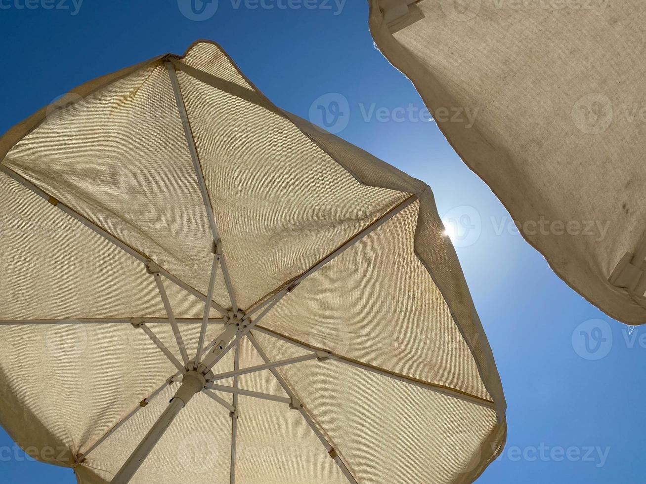 weiße Sonnenschirme vor blauem Himmel foto