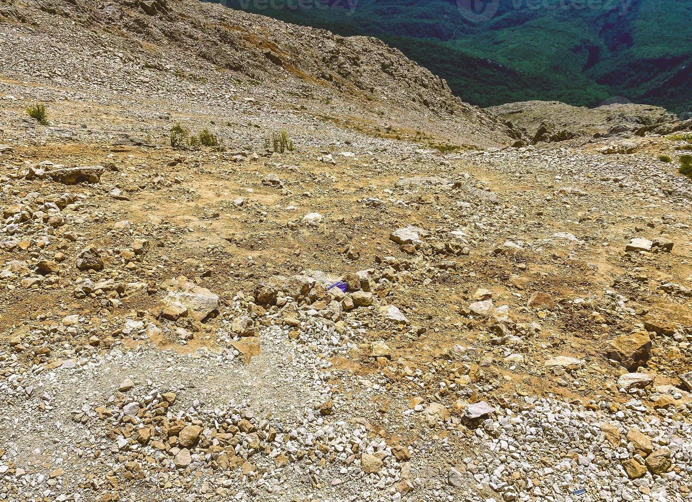 Berge in einem heißen, tropischen Land vor blauem Himmel. Auf den Bergen wachsen grüne Pflanzen. steiler Abstieg mit Steinen und Sand foto