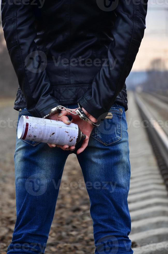 Mädchen in Handschellen mit Sprühdose auf dem Hintergrund einer Eisenbahn t foto