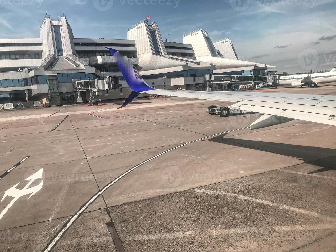 Flughafen mit internationalen Flügen. ein riesiges Gebäude mit Landebahnen im Fenster. In der Nähe befindliche Passagiere im Fenster können das Heck des Flugzeugs sehen foto