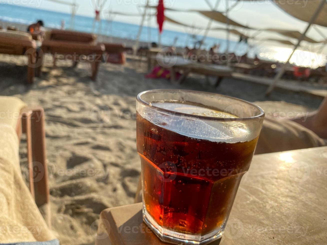 Ein Glas mit einem alkoholfreien Getränk Brauner Cocktail mit Soda und Whiskey auf einem Tisch am Strand am Meer in einem Hotel im Urlaub in einem paradiesischen warmen östlichen tropischen Landresort foto