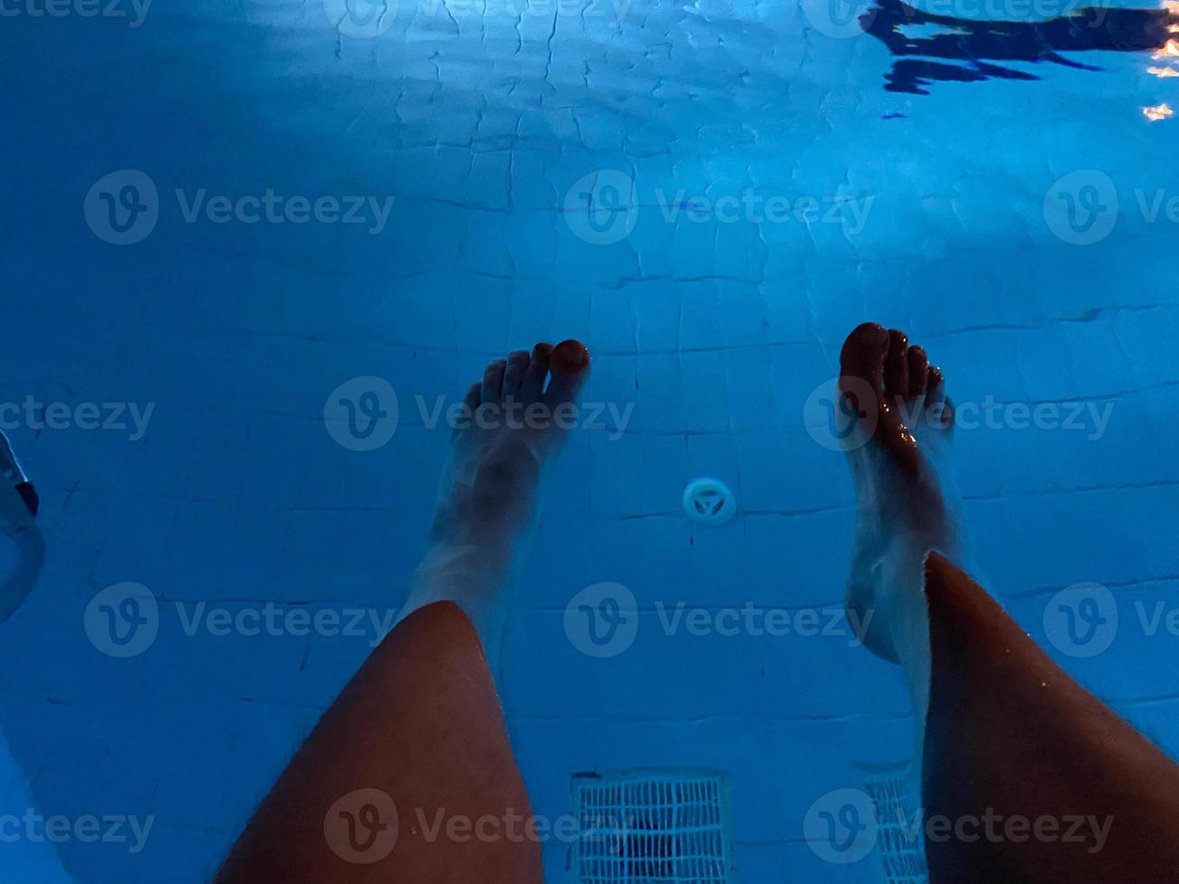 Blick aus der Luft auf die Füße des Mannes, als er gerade in ein klares blaues Schwimmbecken eintaucht foto