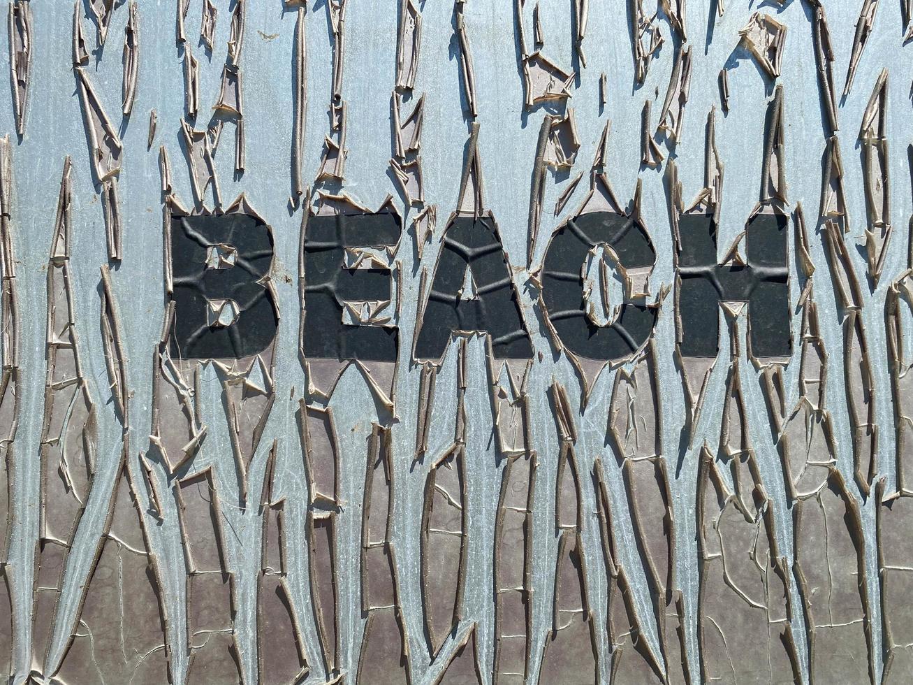 alte rissige Inschrift Strand in großen Buchstaben auf dem Teller. ein brutales Strandurlaubskonzept foto