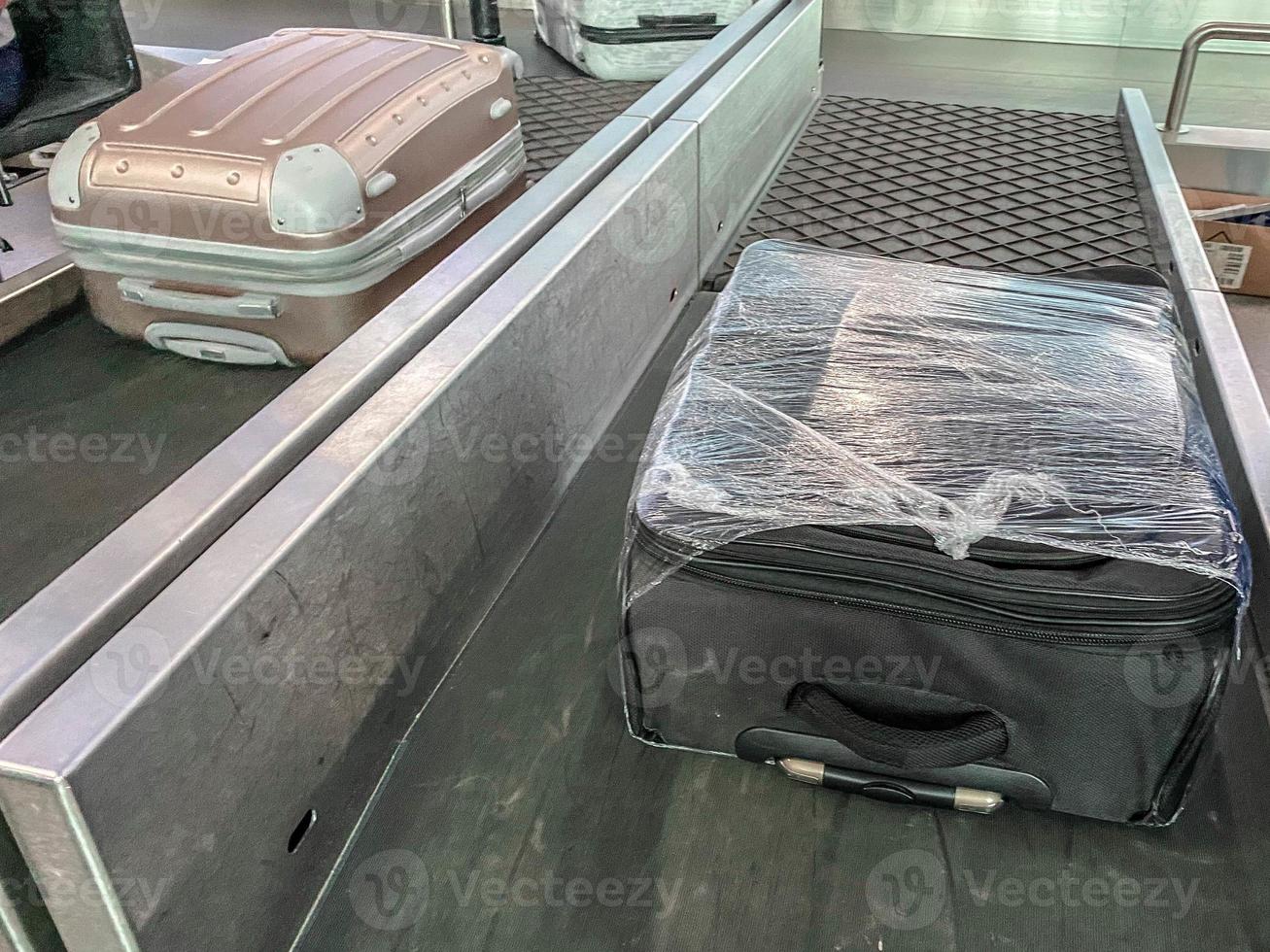 Gepäck auf dem Band am Flughafen. der koffer reist entlang der linie. Dinge sind gestapelt. der koffer ist in einer transparenten folie verpackt. Schutz und Sicherheit von persönlichen Gegenständen foto