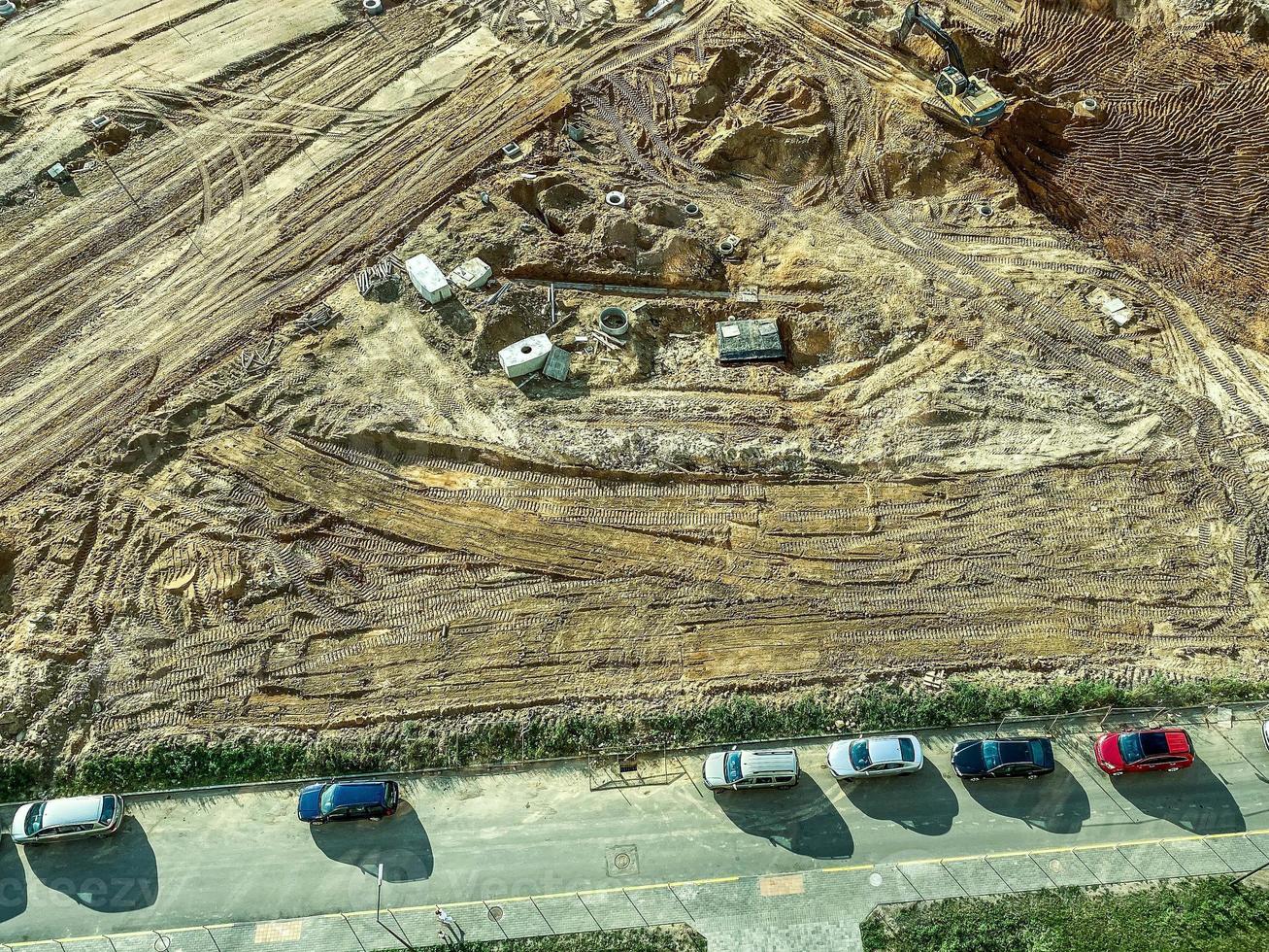 Baufeld aus Sand. ein Ort für den Bau eines Fundaments, ein Feld mit Spuren großer Baumaschinen. Parkplatz in der Nähe foto