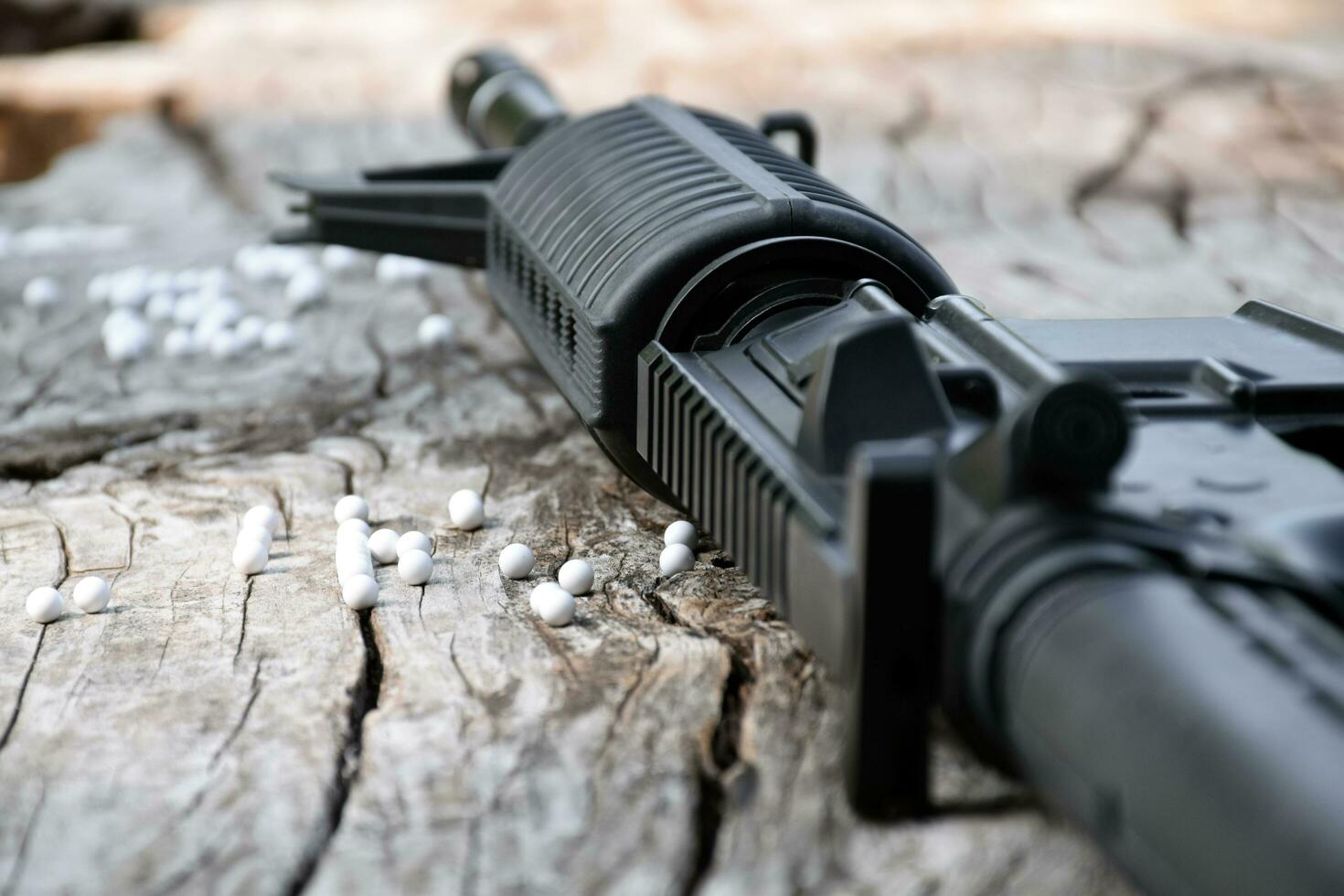 bb-pistole oder airsoft-pistolenmündung und weiße kugeln auf holzbrett, weicher und selektiver fokus. foto