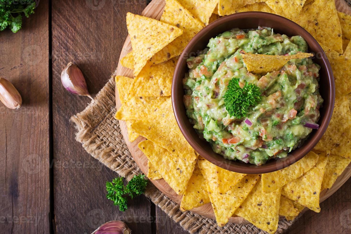 Guacamole Avocado, Limette, Tomate, Zwiebel und Koriander, serviert mit Nachos - traditioneller mexikanischer Snack foto