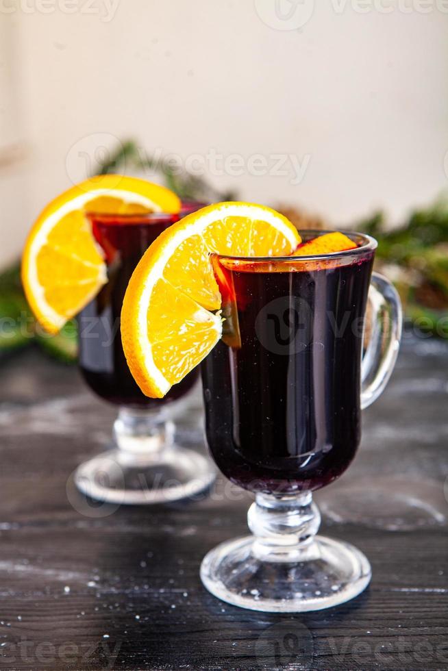 Glas köstlicher Glintwein oder Glühwein, Zimt, Faden auf Vintage-Holzhintergrund. foto