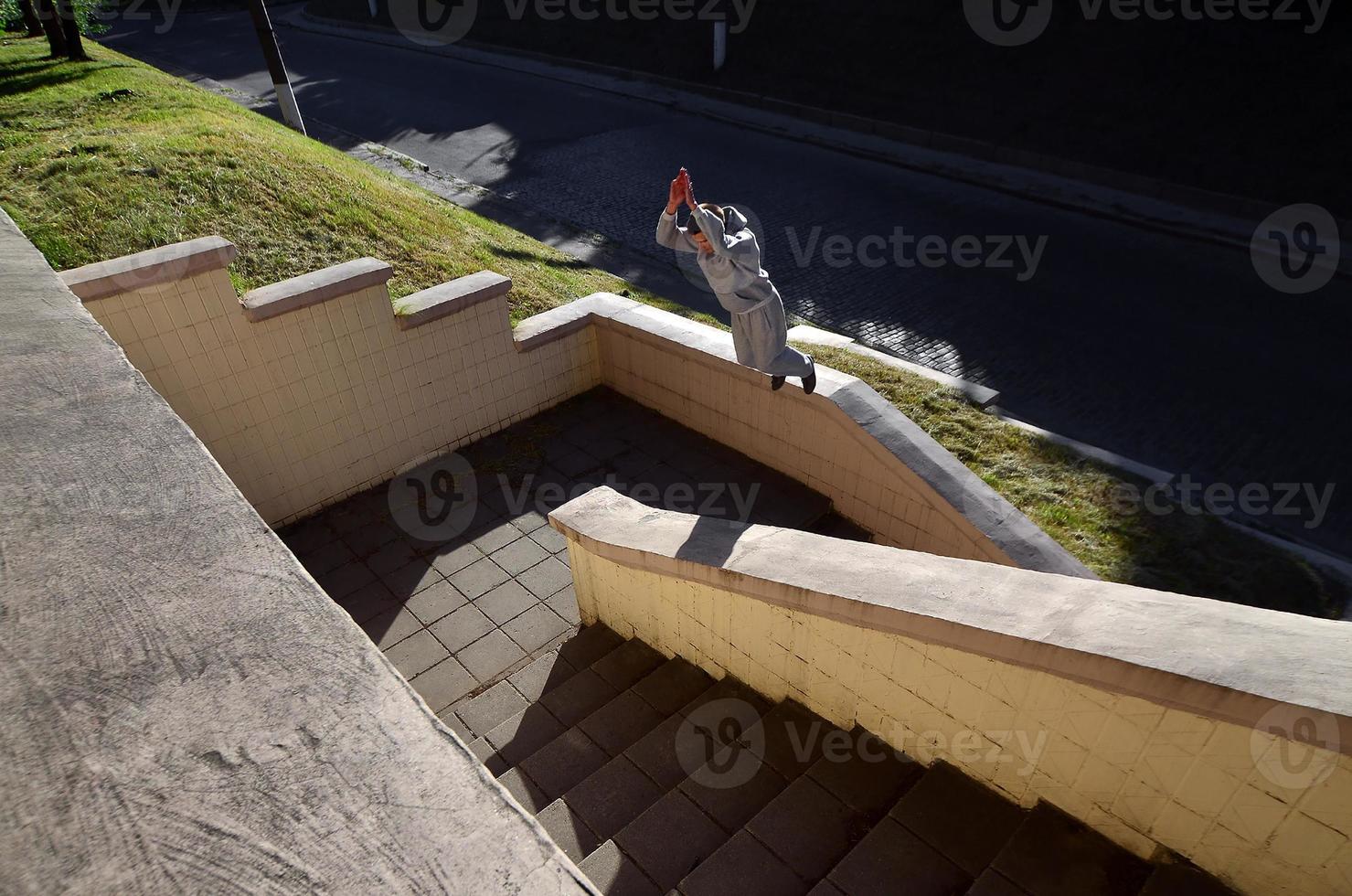 ein junger mann macht einen sprung durch den raum zwischen den betonbrüstungen. Der Athlet übt Parkour und trainiert unter Straßenbedingungen. das Konzept der sportlichen Subkulturen unter Jugendlichen foto