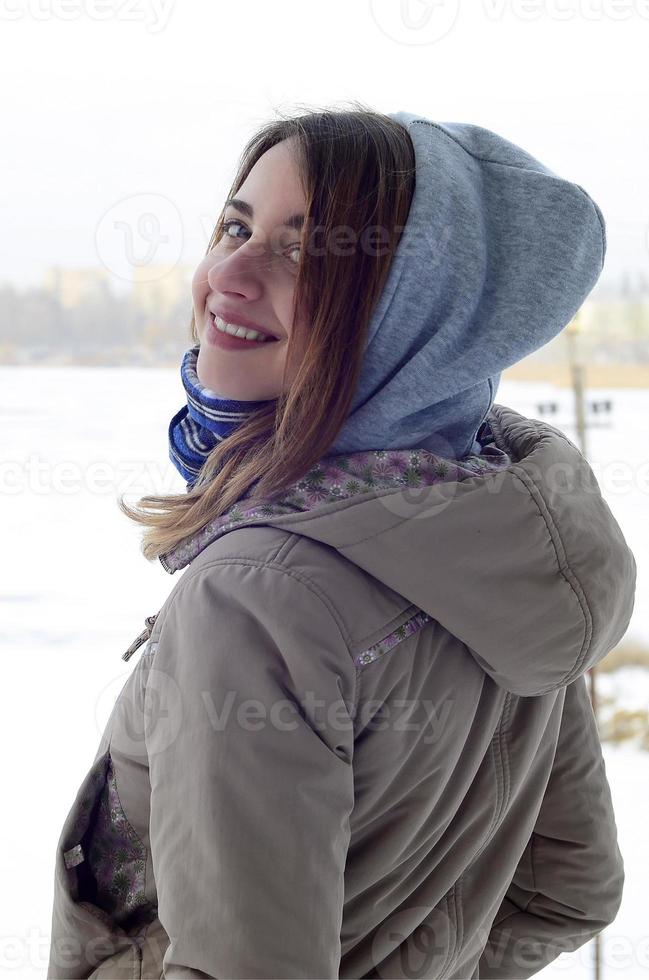 ein junges und lächelndes kaukasisches mädchen schaut im winter um die horizontlinie zwischen dem himmel und dem zugefrorenen see foto