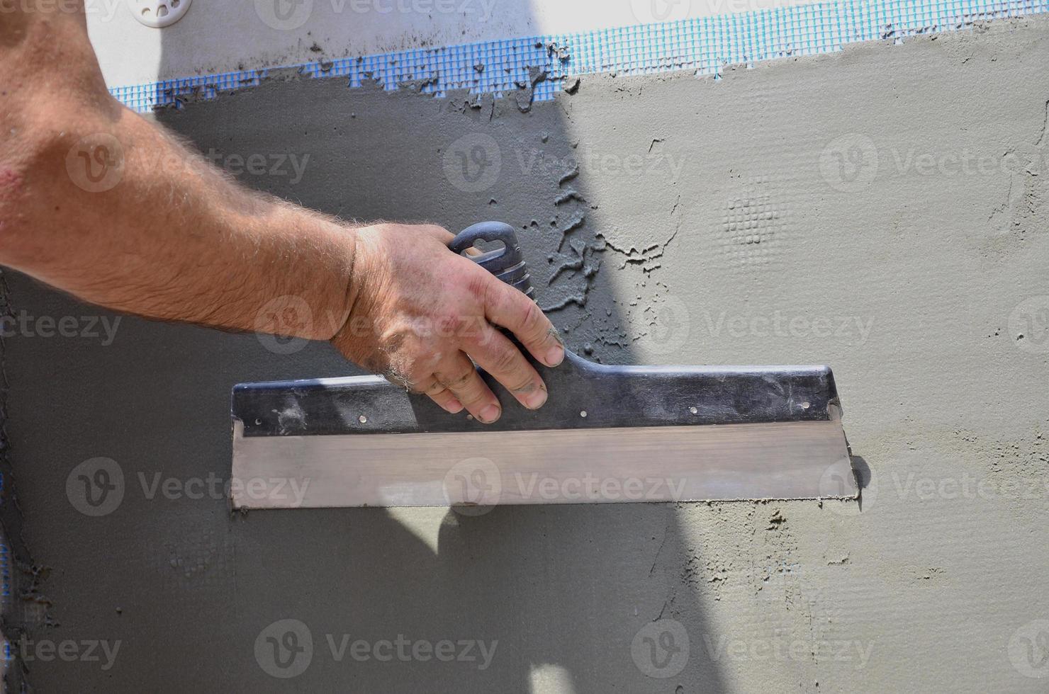 hände eines alten handwerkers mit wandputzwerkzeugen, die haus renovieren. Gipser renovieren Außenwände und Ecken mit Spachtel und Gips. Wanddämmung. Bauabschlussarbeiten foto