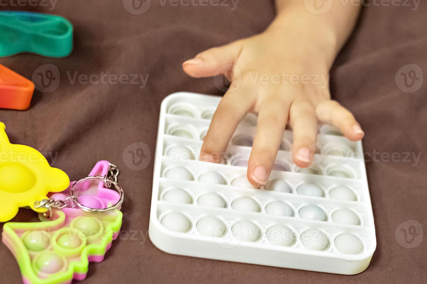 pop it ist ein buntes Anti-Stress-Spielzeug in Kinderhänden. Blasenspiel. Anti-Stress-Spielzeug. foto