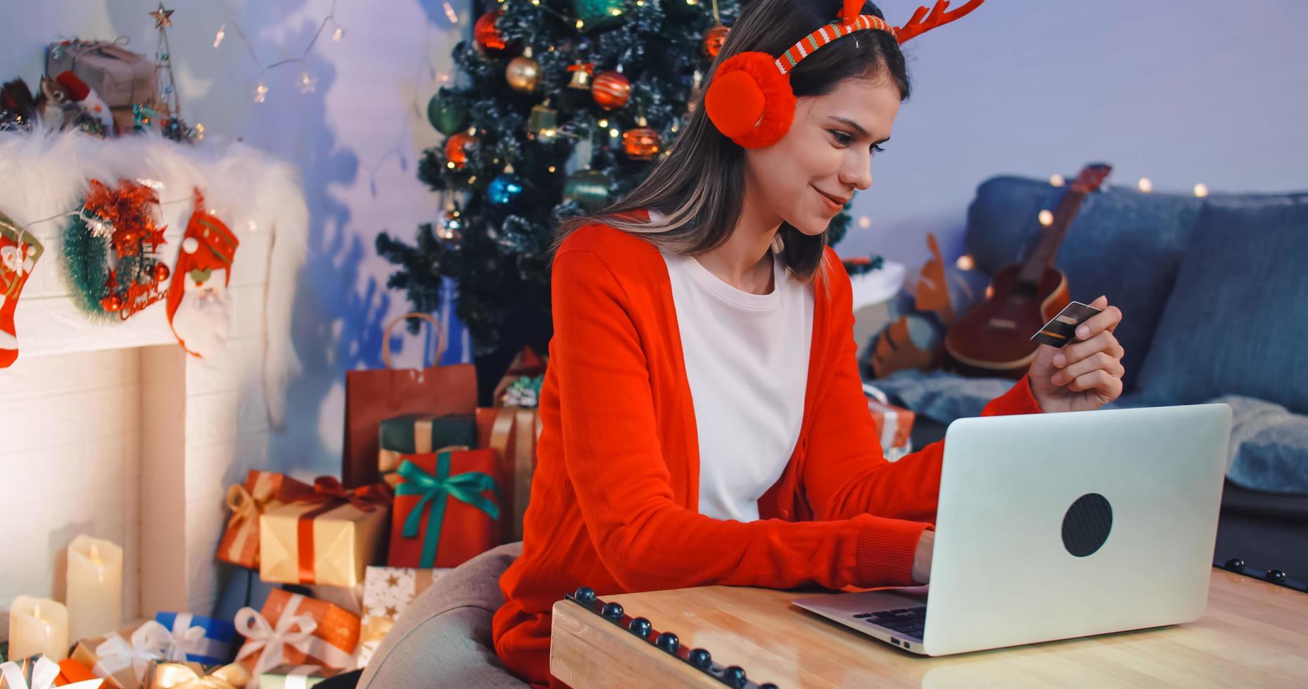 eine junge frau kauft online mit kreditkarte ein, um weihnachtsgeschenke zu kaufen. foto