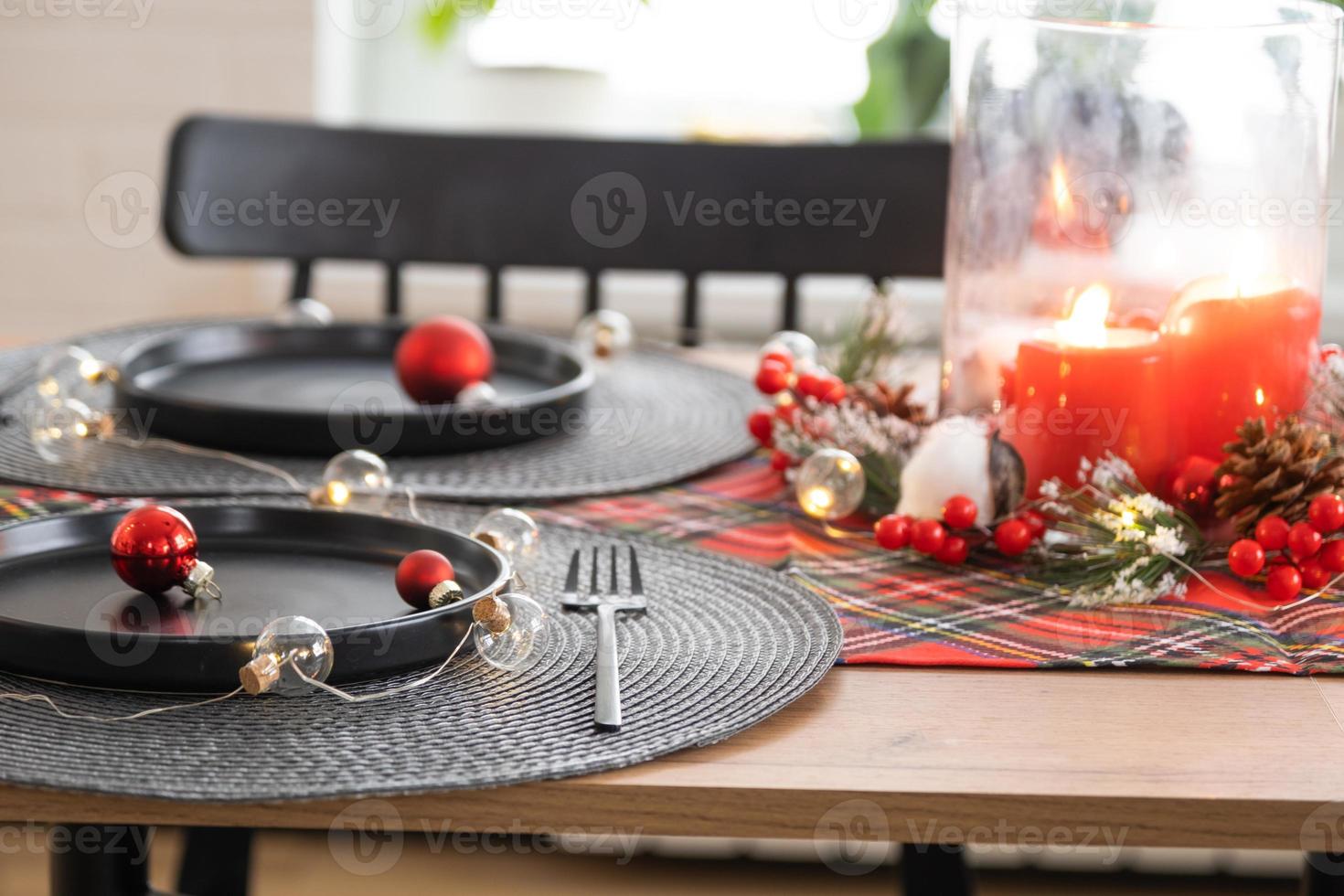 festlich gedeckter tisch im wohnzimmer für weihnachten und neujahr im loft-stil. weihnachtsbaum, schwarze teller und gabeln, gewebte servietten, trendiges geschirr, gemütliches interieur des hauses foto