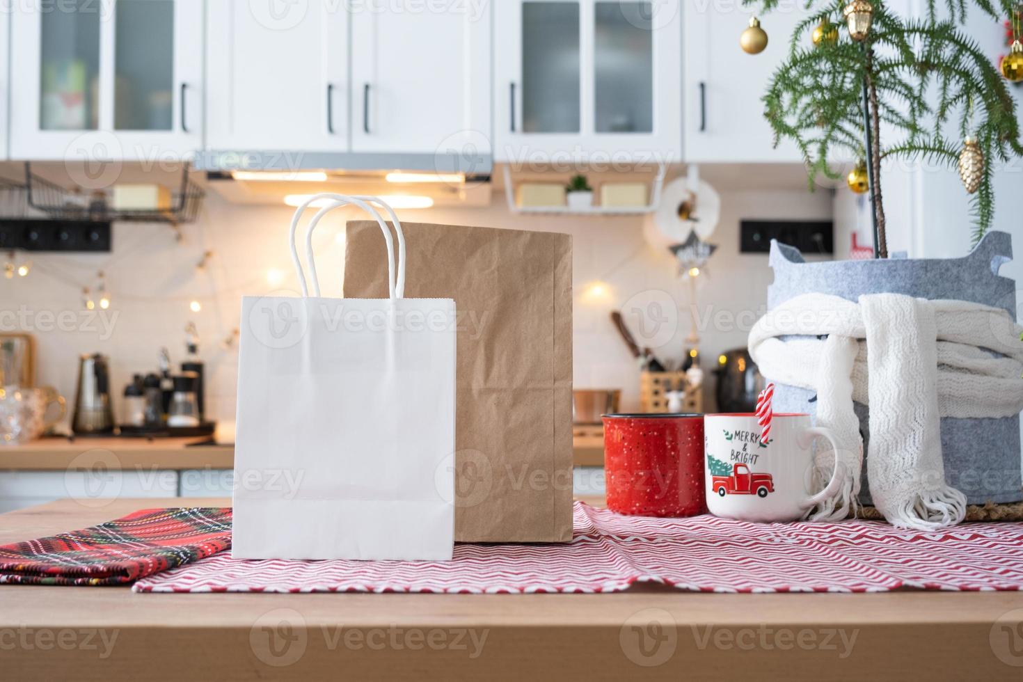 Lebensmittel-Lieferservice-Container auf dem Tisch Weiße Scandi-Festküche im Weihnachtsdekor. Silvesterabend, Zeitersparnis, zu faul zum Kochen, heiße Bestellung, Einweg-Plastikbox in Lichterkette. Attrappe, Lehrmodell, Simulation foto