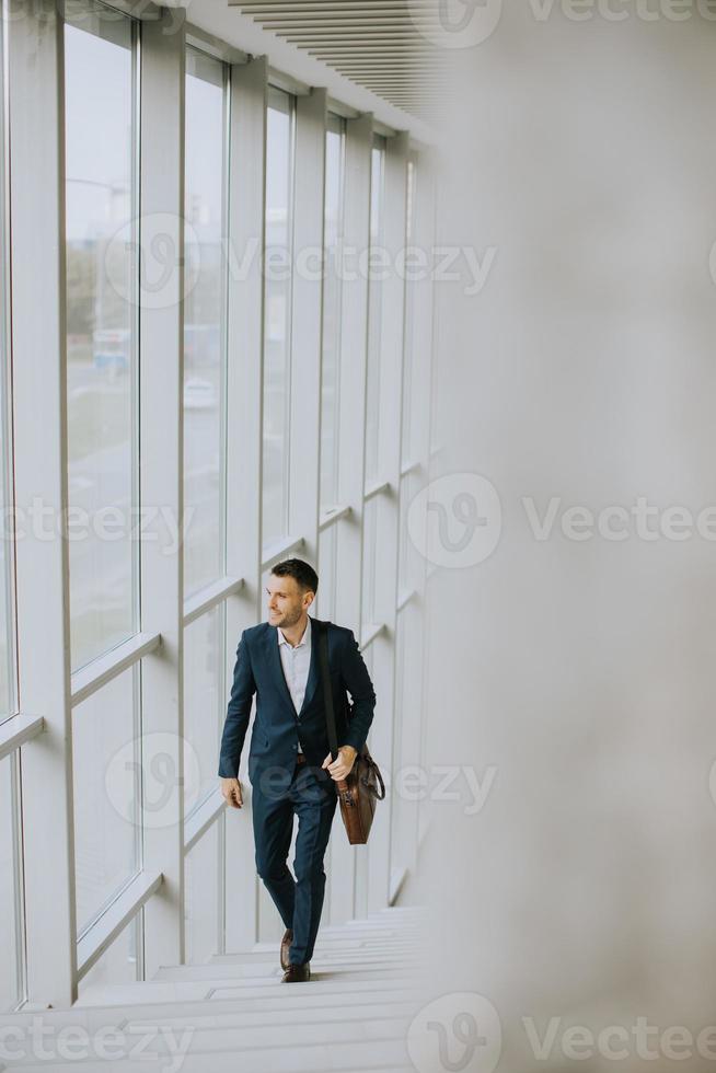 Junger Geschäftsmann mit Aktenkoffer, der die Treppe hinaufgeht foto