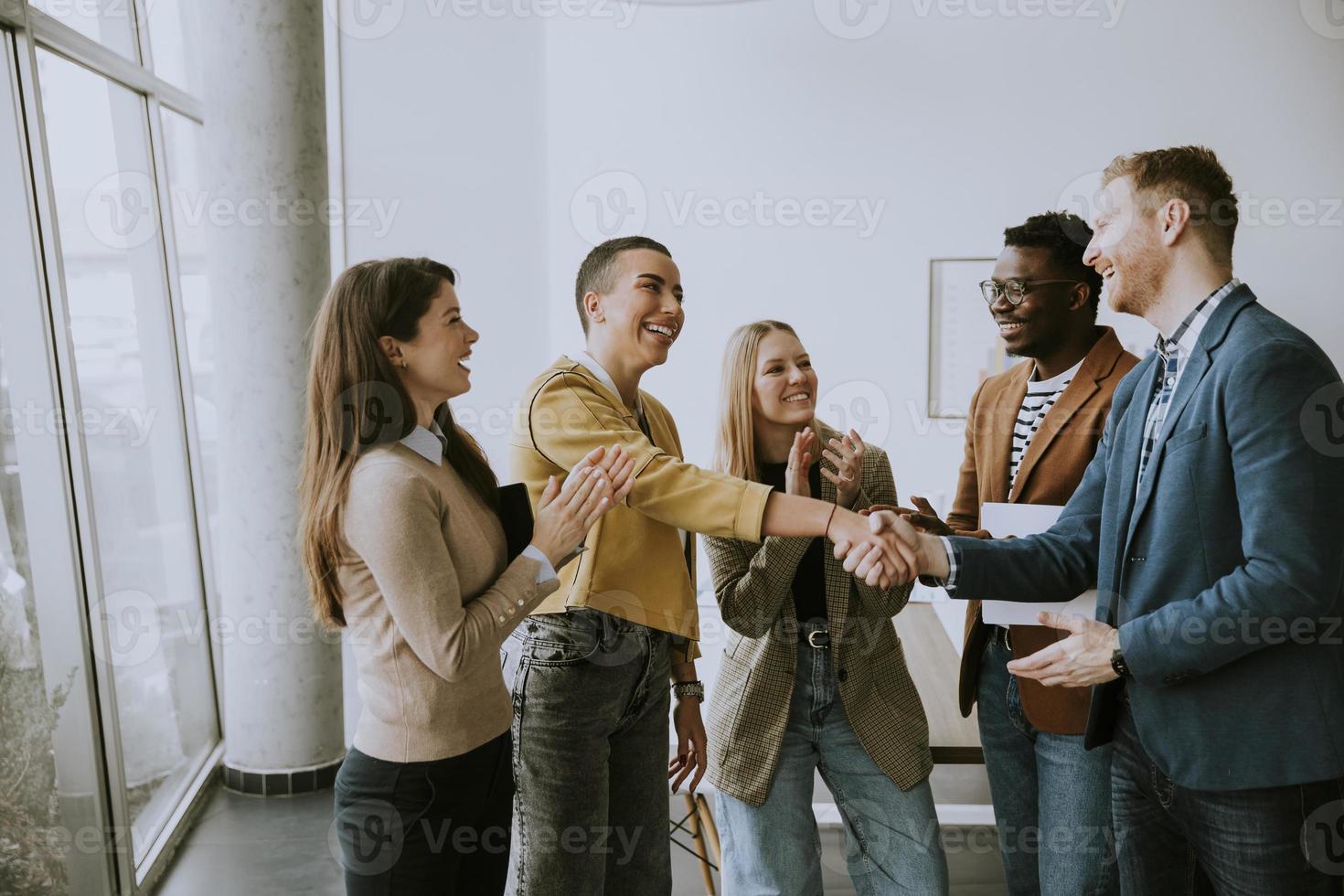 memembers des Kreativteams, das sich bei der Arbeit im modernen Büro die Hände schüttelt foto