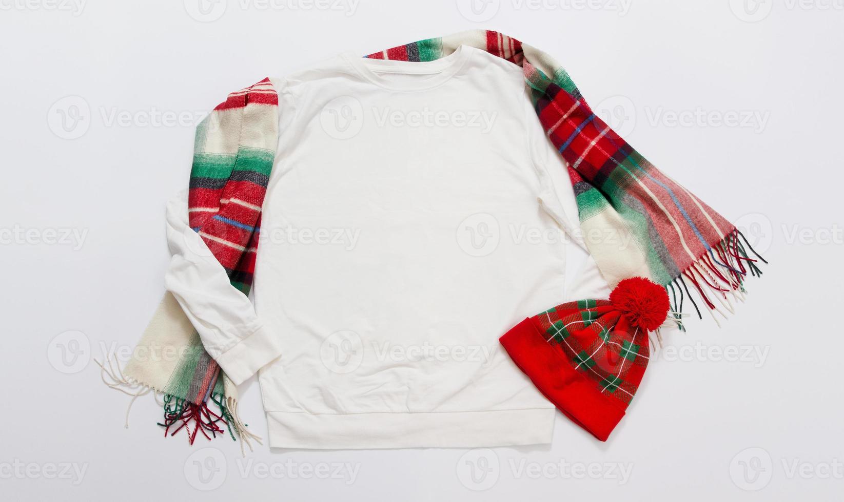 Schließen Sie herauf Fahnen-weißes leeres Schablonensweatshirt mit Kopienraum und Weihnachtsfeiertagskonzept. draufsicht-modell-hoodie und rote feiertagsdekorationen auf weißem hintergrund. frohes neues jahr zubehör. Weihnachten foto