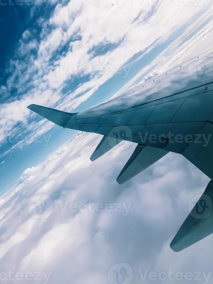 Flügel eines Flugzeugs über Wolken, geneigter Horizont, Blick vom Bullauge foto
