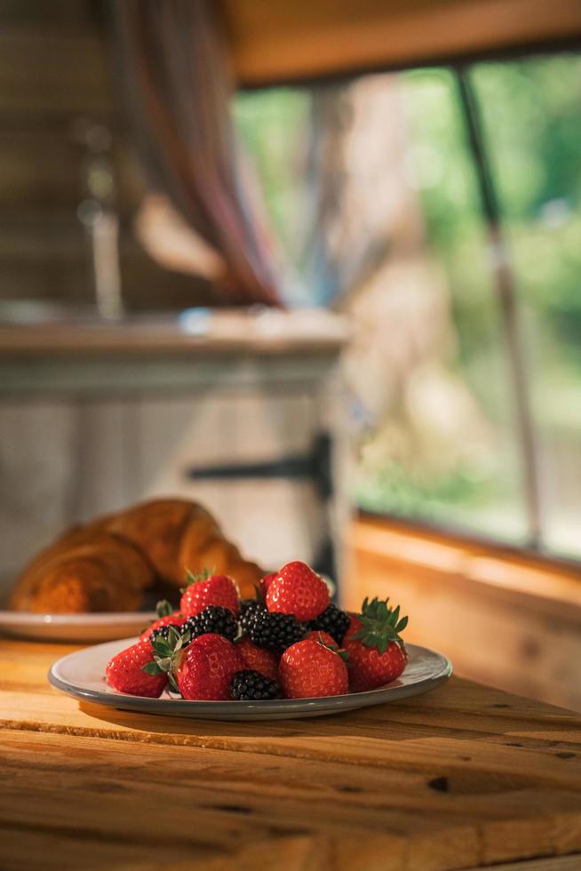 ein Croissant und ein Teller Erdbeeren in einem Wohnmobil. Van Life Camping-Essentials foto