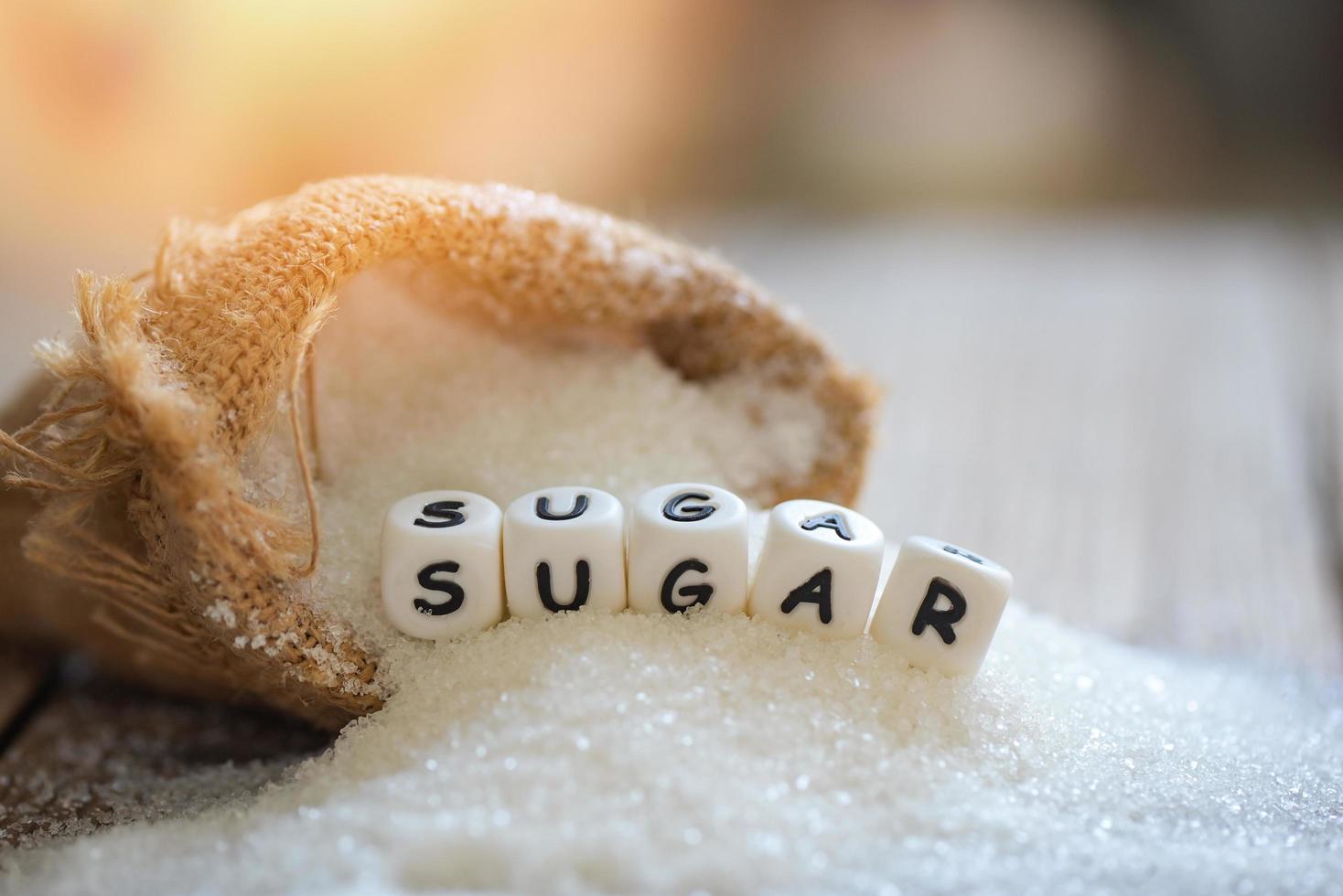 Zucker auf Sack- und Holzhintergrund, Weißzucker für Lebensmittel und Süßigkeiten Dessert Candy Haufen von süßem Zucker kristallin granuliert foto
