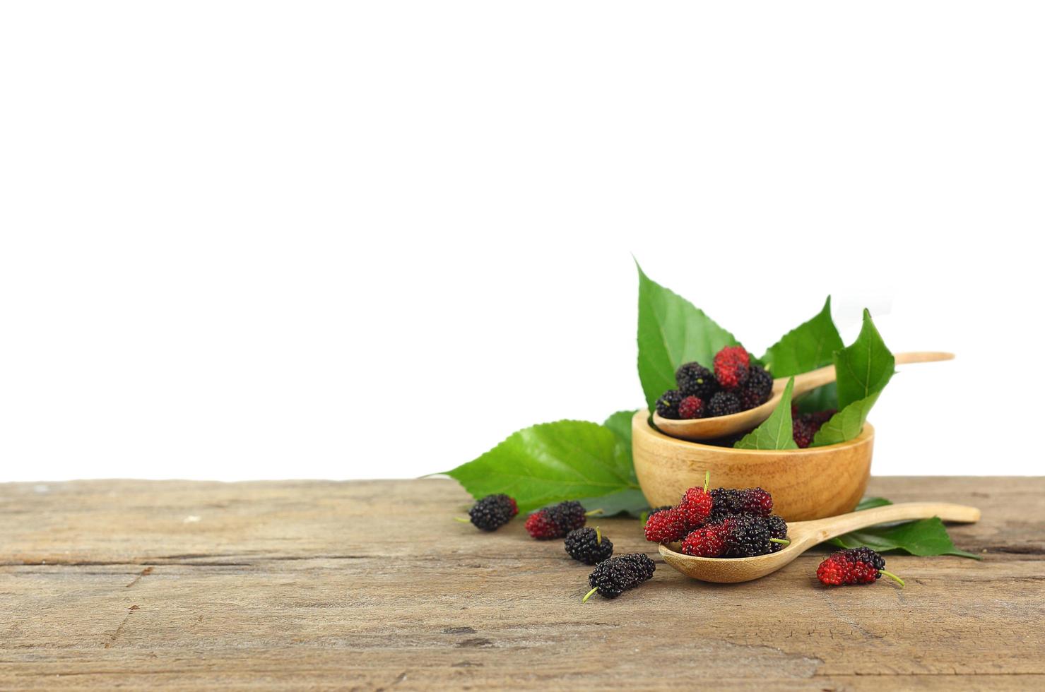 Gruppe von Maulbeeren auf Holztisch isoliert auf weißem Hintergrund foto