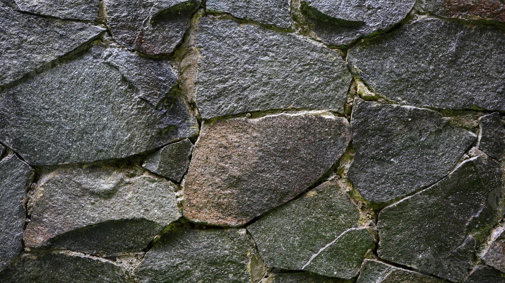 Foto der Steinwandstruktur sieht alt und nass für Tapeten und Hintergrund aus.