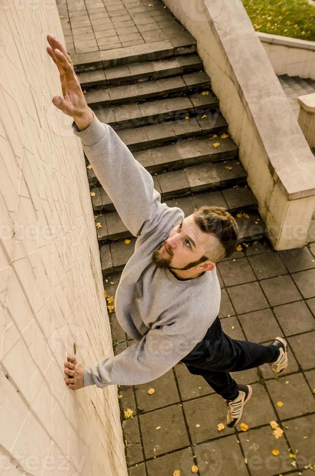 Ein junger Mann überwindet Hindernisse und klettert an Betonwänden. Der Athlet übt Parkour und trainiert unter Straßenbedingungen. das Konzept der sportlichen Subkulturen unter Jugendlichen foto