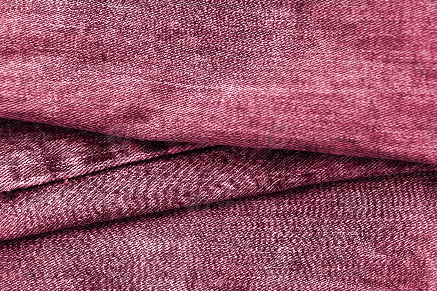 detaillierte abstrakte Textur aus dunkelblauem Jeansstoff. Hintergrundbild eines alten gebrauchten Denim-Hosen-Stoffbildes, getönt in Viva Magenta, Farbe des Jahres 2023 foto
