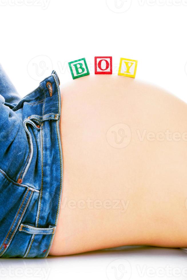 Es ist ein Jungenkonzept mit Druckbuchstaben auf schwangerem Bauch foto