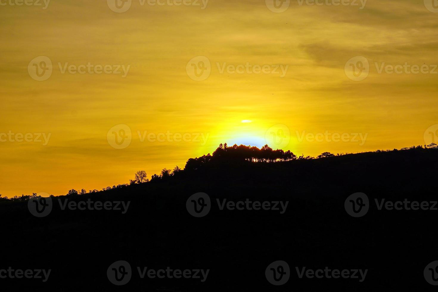 der blick auf die sonne, die in der dämmerung in goldgelb untergeht, schöner kontrast zu den schwarzen bergen in der dämmerung. weicher und selektiver Fokus. foto