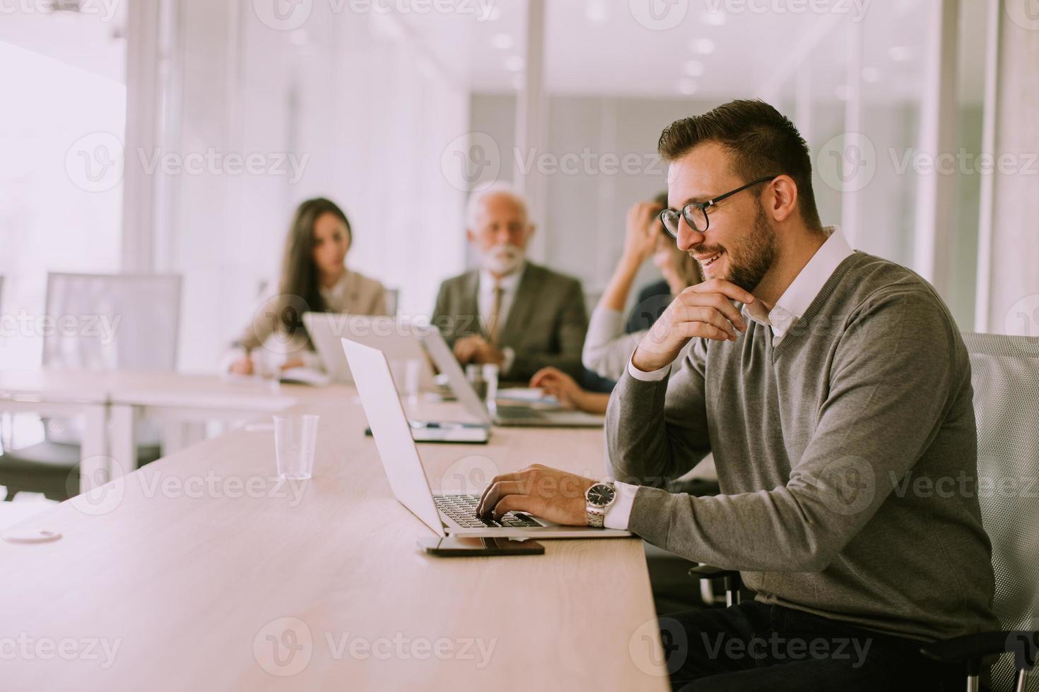 Junger Geschäftsmann, der im Büro am Laptop arbeitet foto