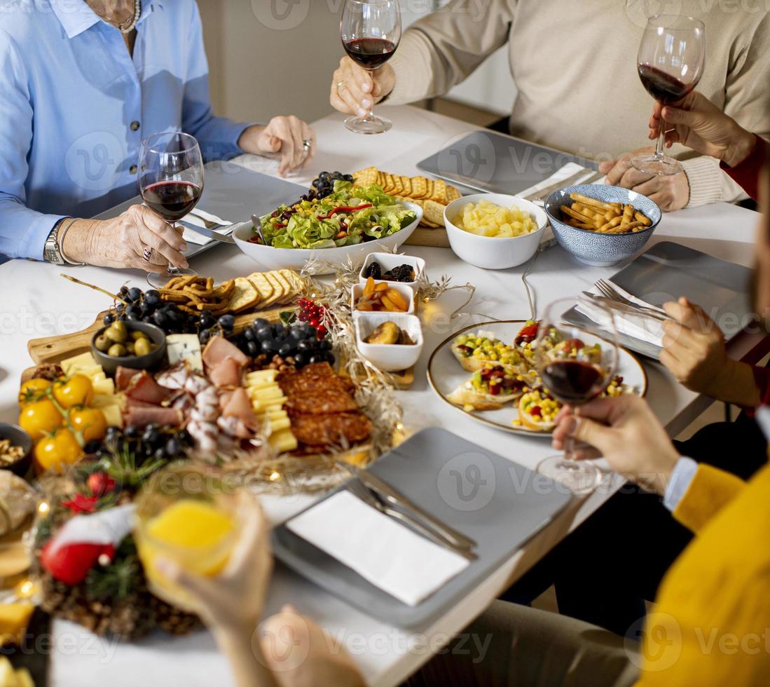 glückliche familie, die zu hause mit rotwein zu abend isst foto