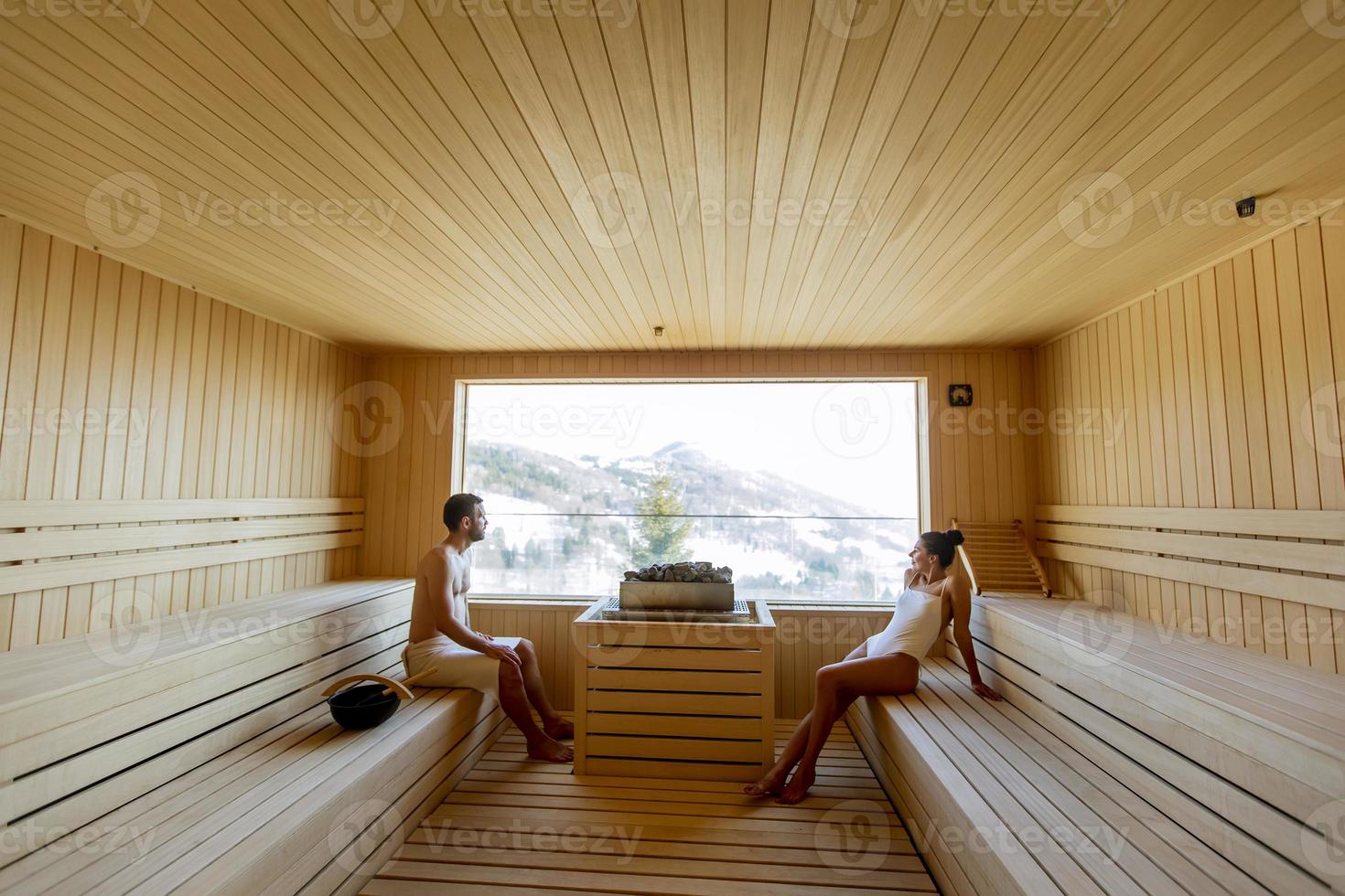 junges paar entspannt sich in der sauna und beobachtet den winterwald durch das fenster foto