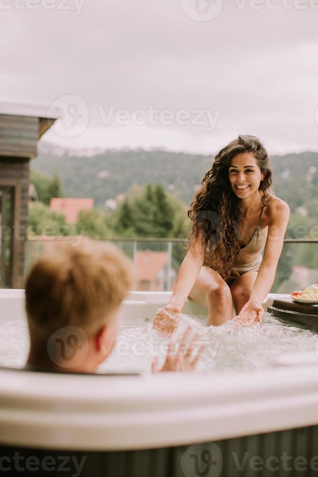 junges Paar, das im Urlaub im Whirlpool im Freien genießt foto