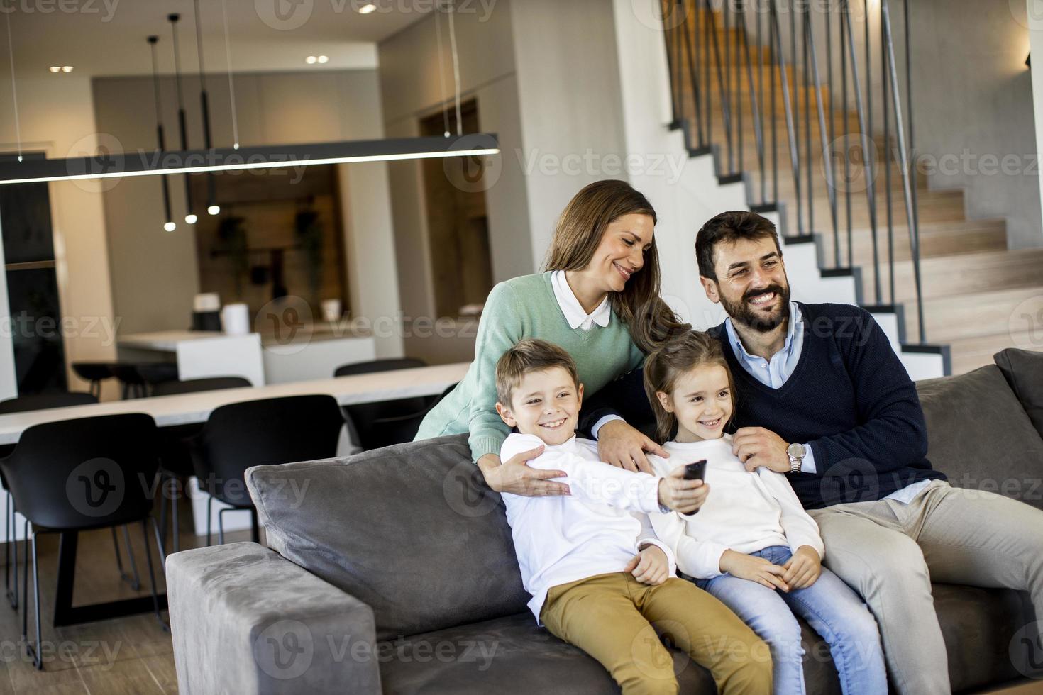 junge familie, die zusammen auf dem sofa im wohnzimmer fernsieht foto