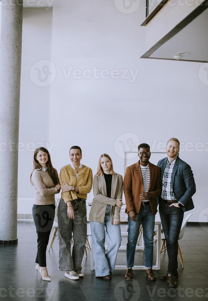 Gruppe positiver Geschäftsleute, die im Büro zusammenstehen foto