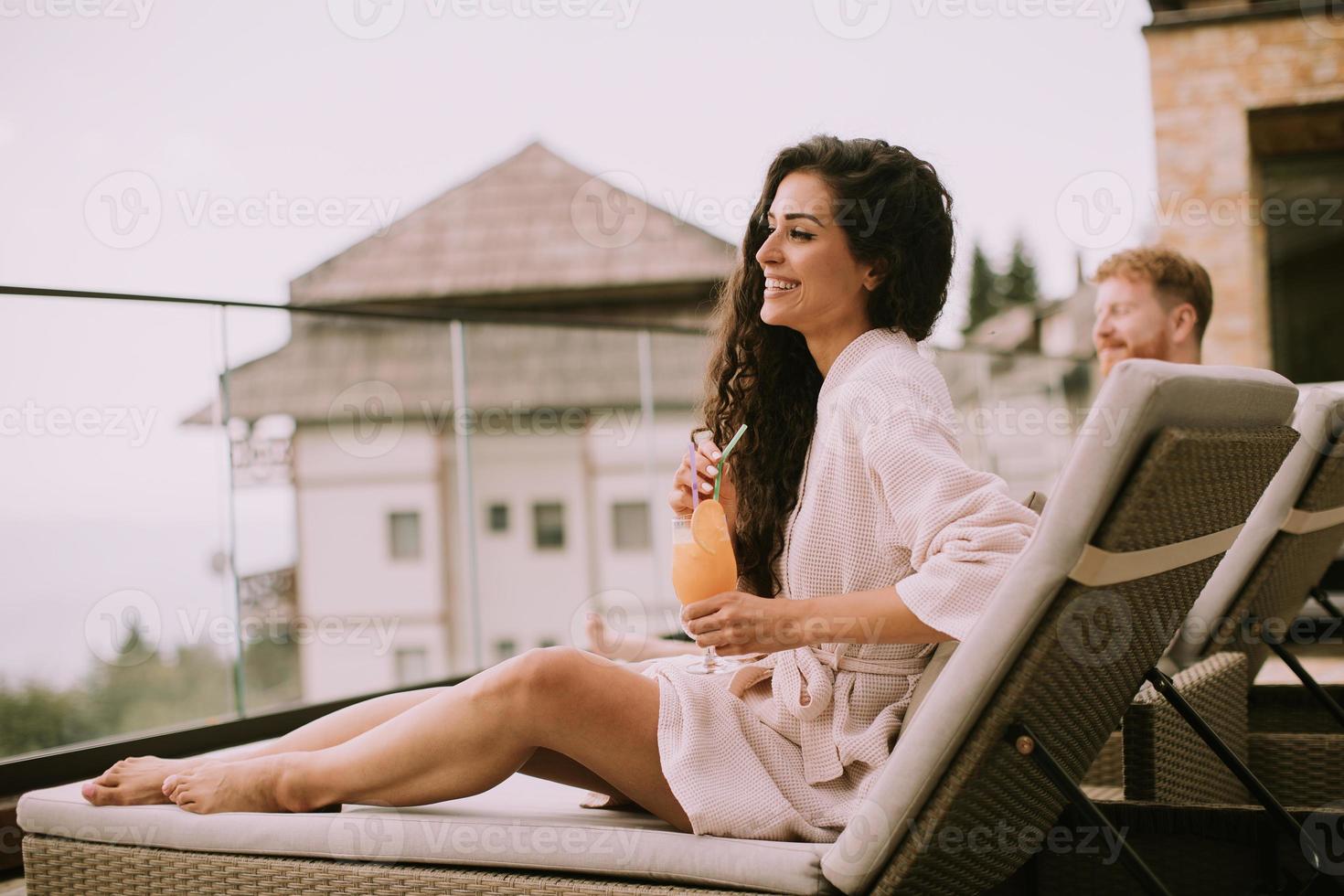 junges Paar entspannt sich auf Betten und trinkt frischen Orangensaft auf der Außenterrasse foto