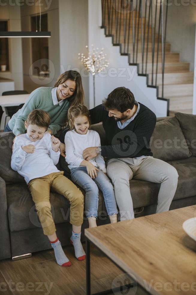 Glückliche Familie mit zwei Kindern genießt die gemeinsame Zeit auf der Couch im Wohnzimmer foto