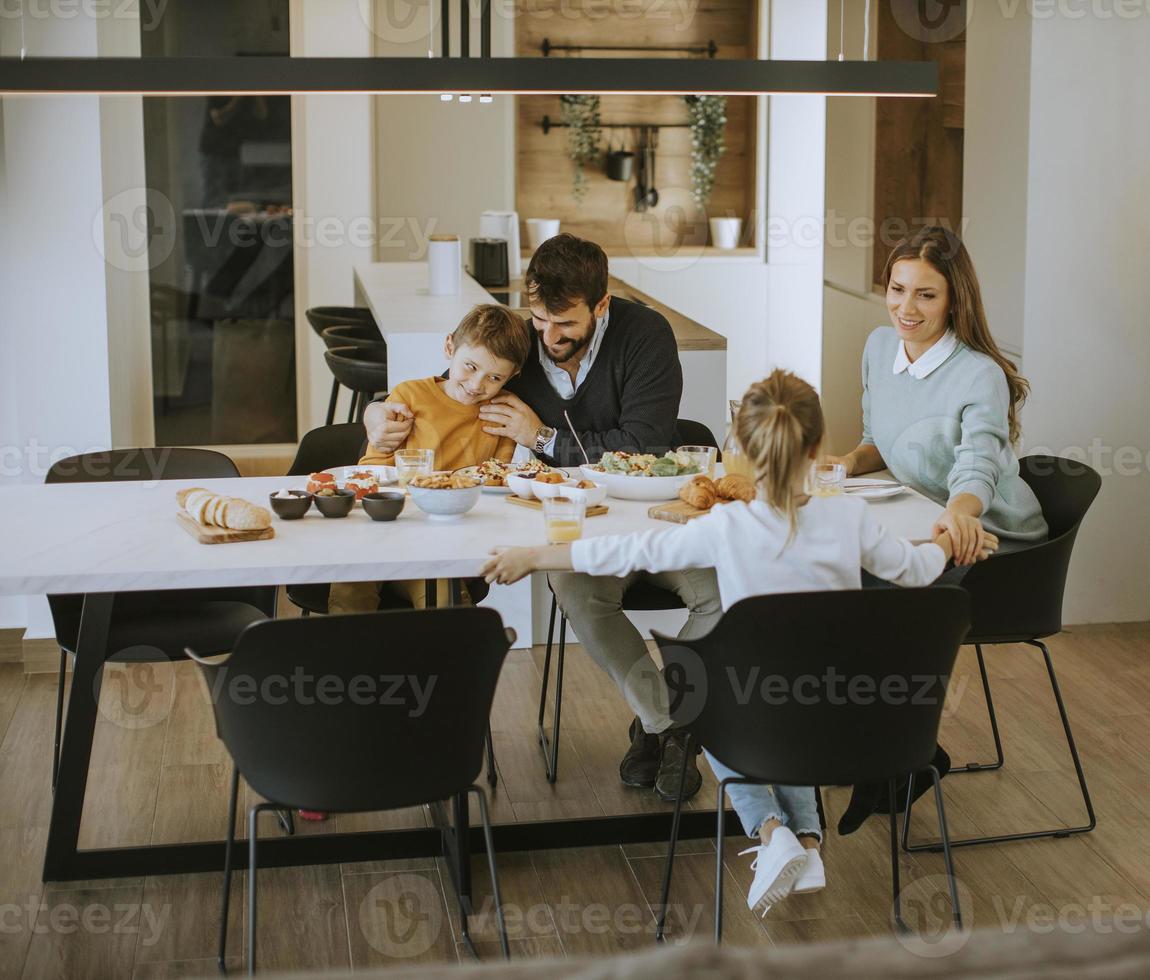 Junge glückliche Familie spricht beim Mittagessen am Esstisch foto