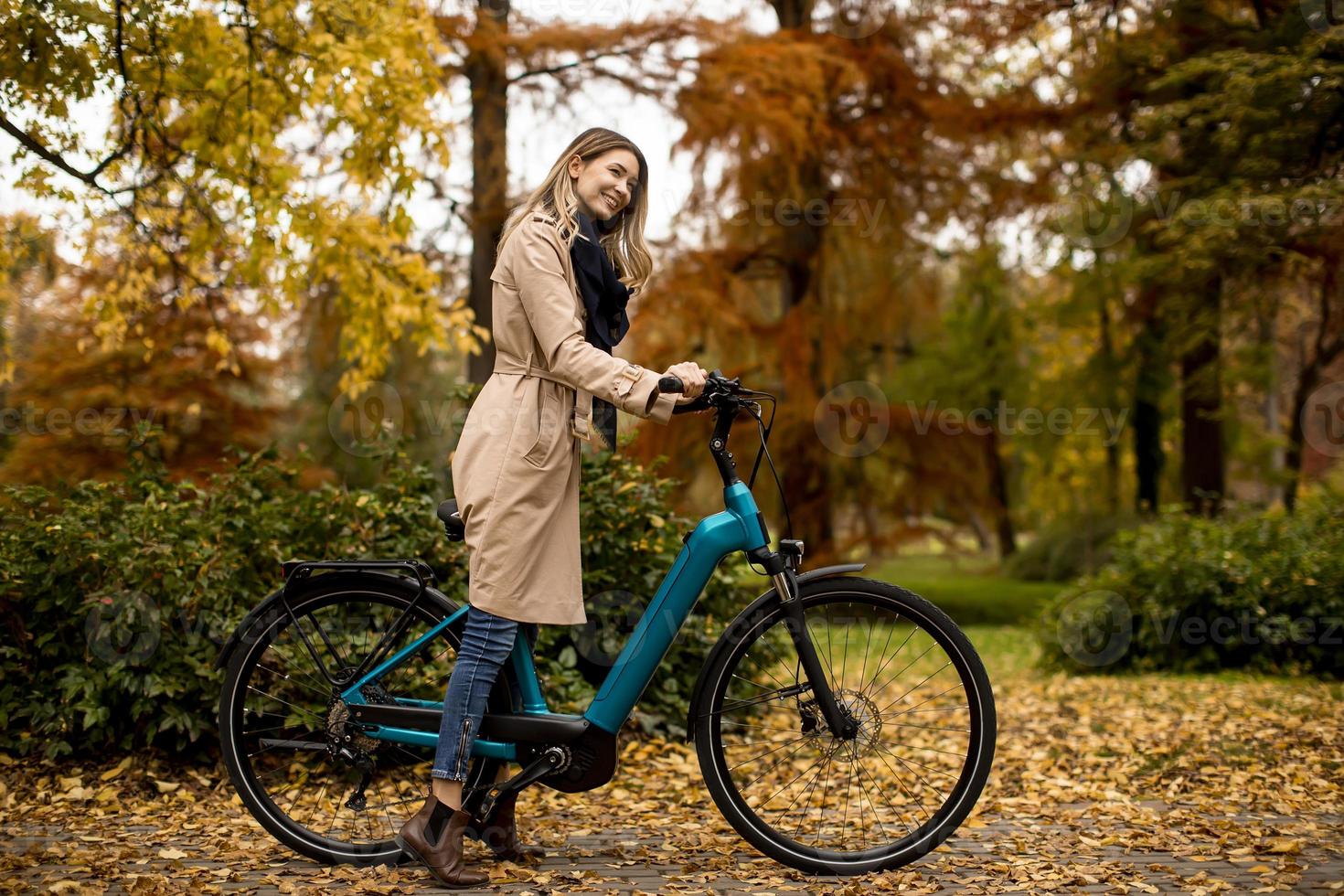 junge Frau mit Elektrofahrrad im Herbstpark foto