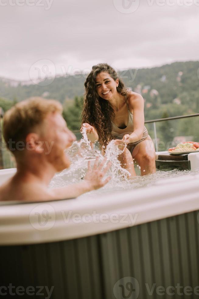 junges Paar, das im Urlaub im Whirlpool im Freien genießt foto