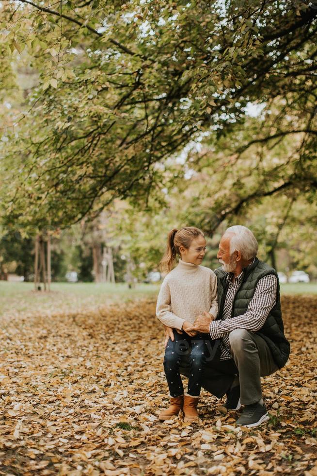 Großvater verbringt am Herbsttag Zeit mit seiner Enkelin im Park foto