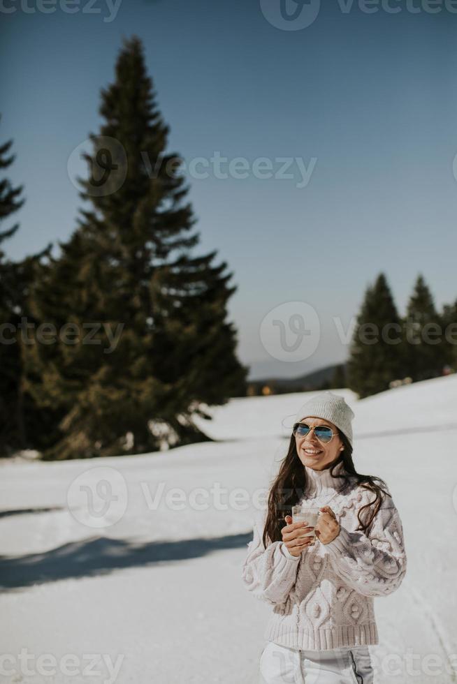 junge frau, die limonade auf der bergskispur trinkt foto