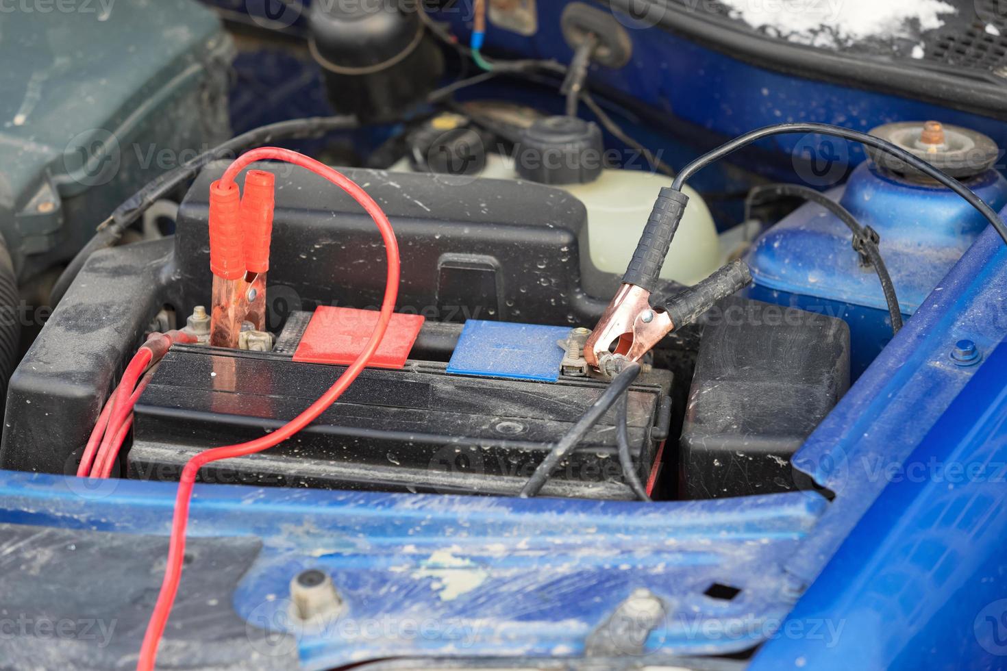 Anschließen von Hochspannungskabeln an die Autobatterie. Laden einer entladenen Autobatterie foto