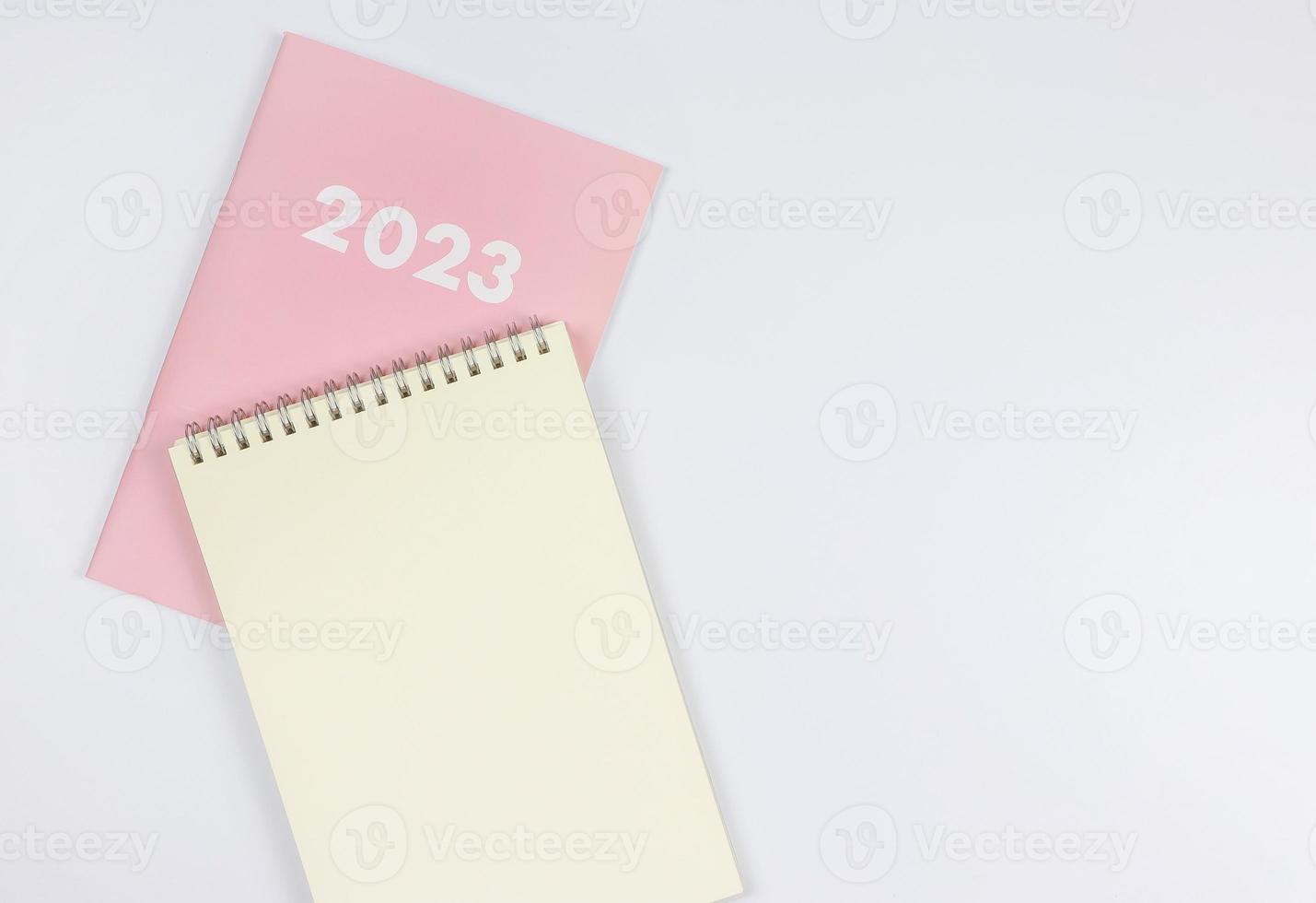 Flaches Notizbuch aus leerem Papier auf rosafarbenem Tagebuch 2023 auf weißem Hintergrund. foto