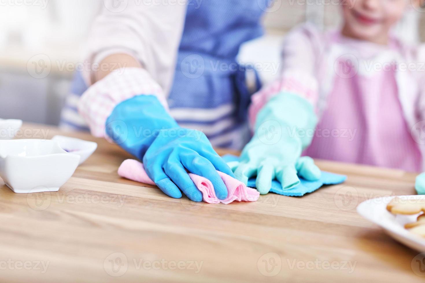 Kleines Mädchen und ihre Mutter in Schürzen putzen die Küche foto