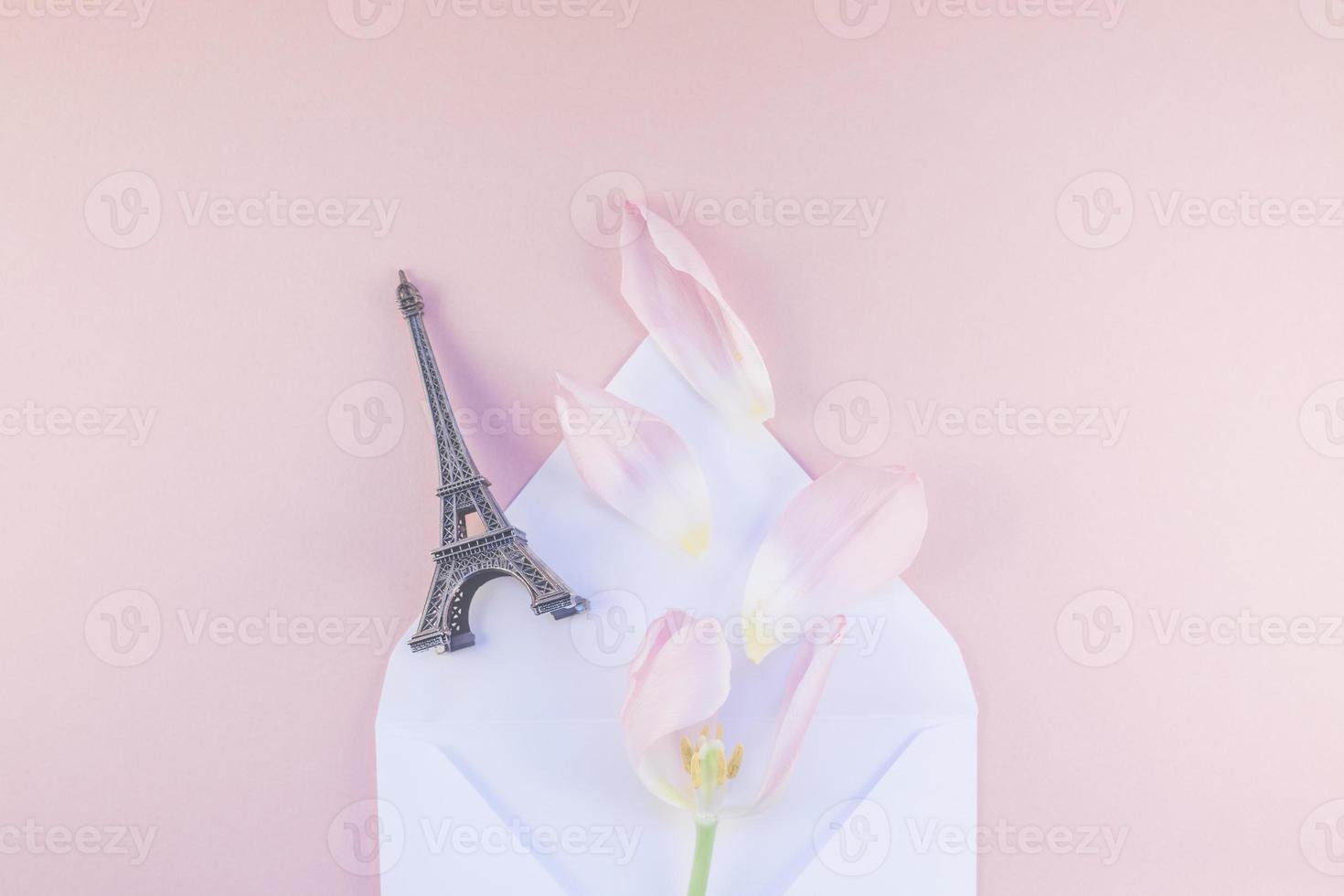 rosa tulpe im umschlag mit eiffelturmminiatur foto