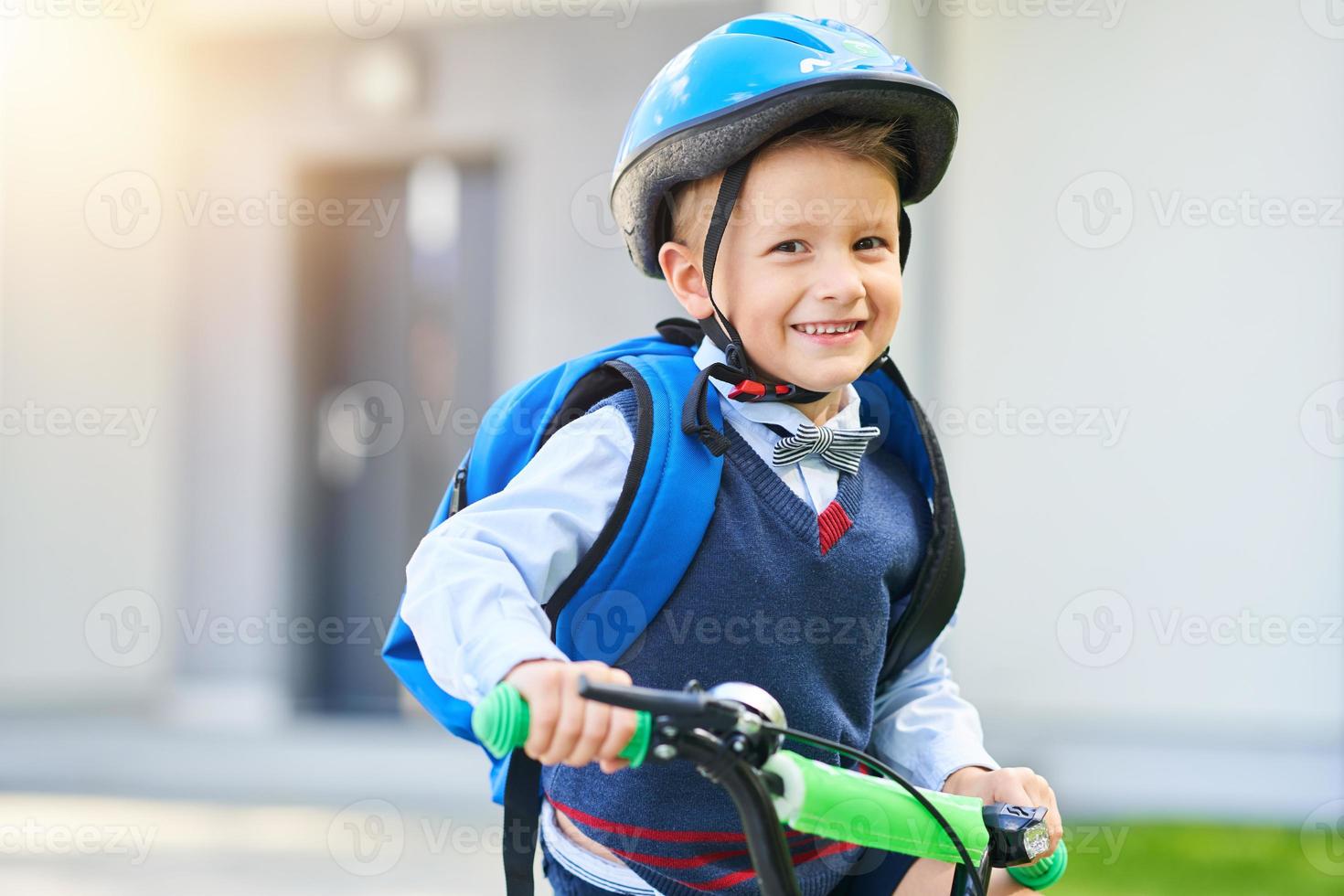 schuljunge im schutzhelm, der fahrrad mit rucksack fährt foto